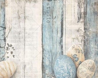 May include: A rustic Easter-themed composition featuring three decorative eggs with floral patterns. The eggs are in shades of blue, cream, and yellow, set against a backdrop of weathered, light blue and white wooden planks. The word "studio" is visible.