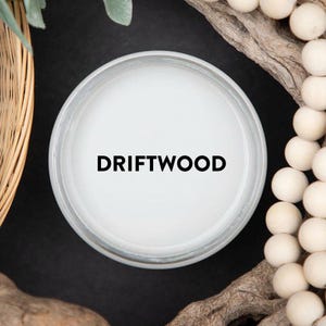 May include: A white candle jar with a black label that reads "DRIFTWOOD".