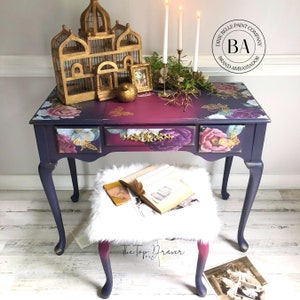 A vintage vanity desk and stool refurbished by The Top Drawer, a Dixie Belle Paint Company Brand Ambassador, is painted dark purple and pink and features the Floral Romance transfer on it.