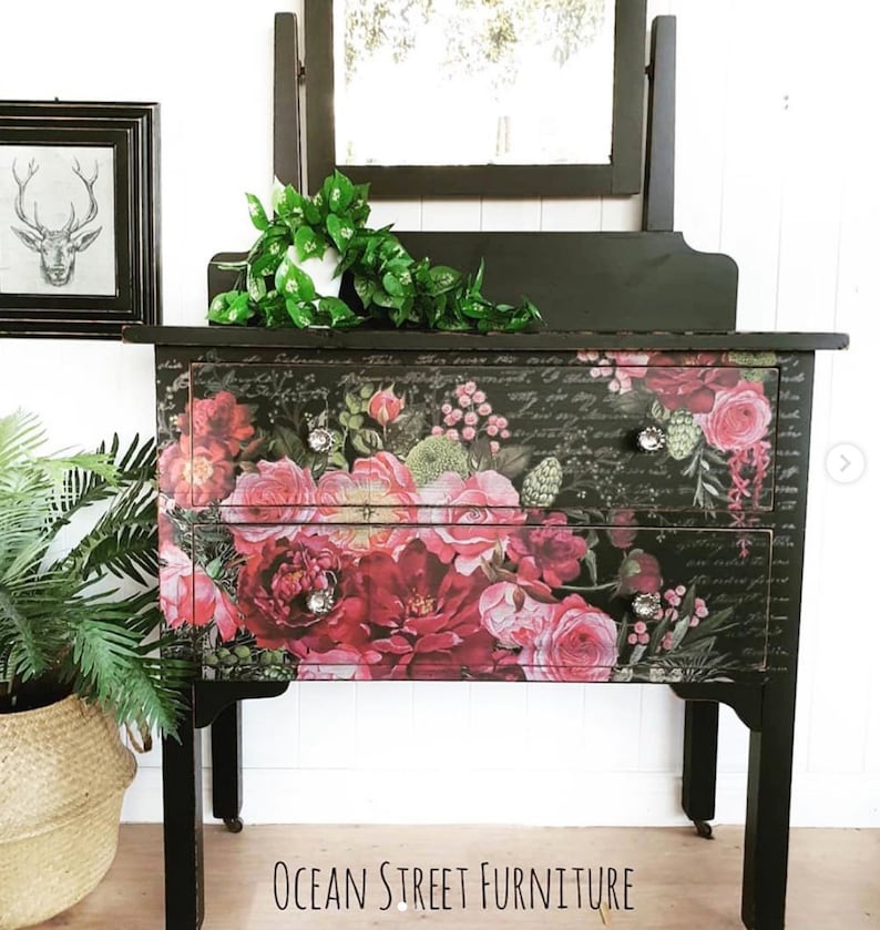 A vintage dresser painted black with roses across the front in different shades of pink. On the bottom, in black lettering, it reads Ocean Street Furniture.