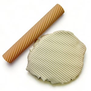 May include: A brown textured rolling pin with a white clay imprint showing the texture of the rolling pin.