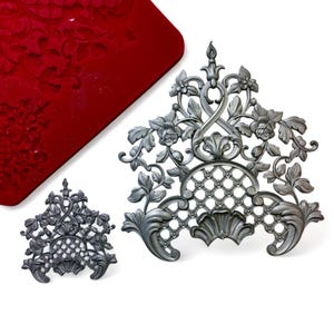 May include: Two silver-colored metal molds with intricate floral and lattice designs. The larger mold is approximately 10 inches tall and the smaller mold is approximately 5 inches tall. Both molds are made of a durable metal and are perfect for creating decorative accents for cakes, cupcakes, and other desserts.