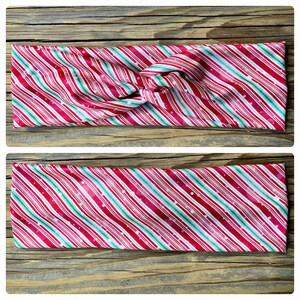 May include: A red and green striped headband with white polka dots. The headband is made of a soft, stretchy fabric and is perfect for adding a festive touch to any outfit.
