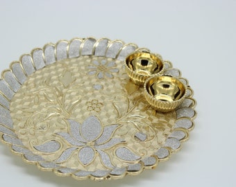 May include: A gold-colored metal serving tray with a decorative floral design and two small gold-colored bowls. The tray has a scalloped edge and a glittery finish.