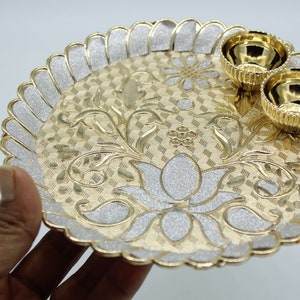 May include: A gold and silver decorative plate with a floral design and two small bowls. The plate has a scalloped edge and a raised design.