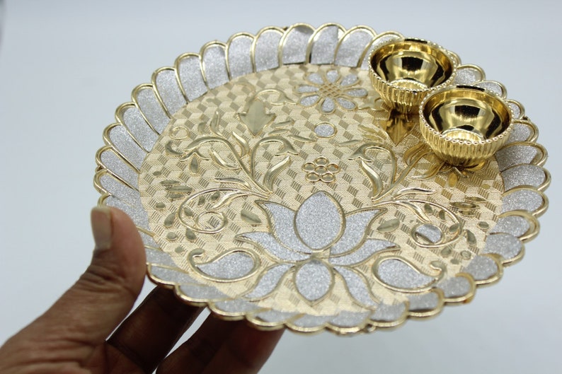 May include: A gold and silver decorative plate with a floral design and two small bowls. The plate has a scalloped edge and a raised design.