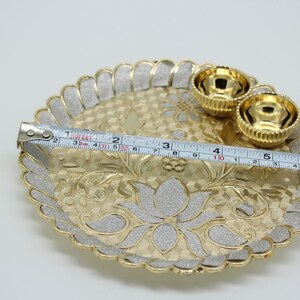 May include: A gold-coloured metal tray with a decorative design and two smaller bowls. The tray is 15 cm in diameter.