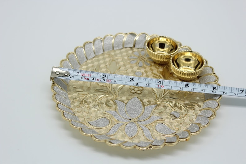 May include: A gold-coloured metal tray with a decorative design and two smaller bowls. The tray is 15 cm in diameter.