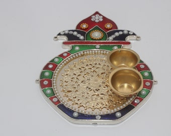 May include: A decorative metal plate with a gold-colored center and a colorful design around the edge. The plate has two small bowls on the side, and the design features red, green, blue, and white colors.