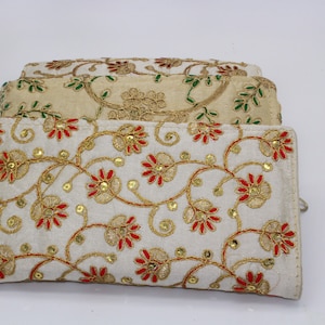 May include: A set of three embroidered clutches in white, cream, and beige with floral patterns. The clutches have gold and red embroidery and sequins.