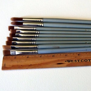 May include: A set of ten gray paint brushes with brown bristles, arranged in order of size, with a wooden ruler labeled "Westcott" underneath.