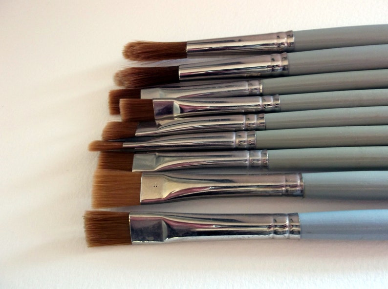 May include: A set of eight paint brushes with silver metal ferrules and light blue wooden handles. The brushes have different sizes and shapes of bristles.