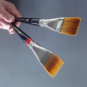 May include: Two flat paint brushes with black handles and silver ferrules. The brush on top has the text "PRO OIL TEMPERA-ART" printed on the handle. The brush on the bottom has the text "PRO OIL TEMPERA-ART" printed on the handle.