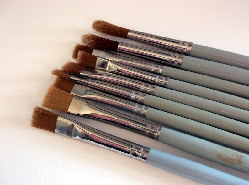 May include: A set of ten paint brushes with light blue handles and silver ferrules. The brushes have different sizes and shapes of bristles.