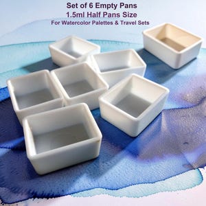 May include: A set of six empty white plastic half pans for watercolor palettes and travel sets, each with a 1.5ml capacity. The rectangular containers are arranged in a cluster, featuring clean edges and a hollow interior for paint storage.