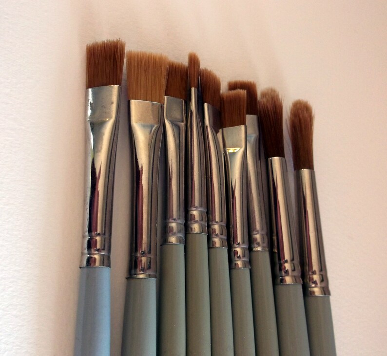 May include: A set of ten paint brushes with silver metal ferrules and light blue wooden handles. The brushes have various sizes and shapes of bristles.