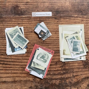 K&ouml;nnte beinhalten: Eine Sammlung von Vintage-Ephemera, darunter kleine Fotografien und bedruckte Karten, angeordnet auf einer Holzoberfl&auml;che. Der Text "HISTORICAL HOME" ist sichtbar. Die Bilder weisen Schwarz-Wei&szlig;- und Sepia-T&ouml;ne auf.