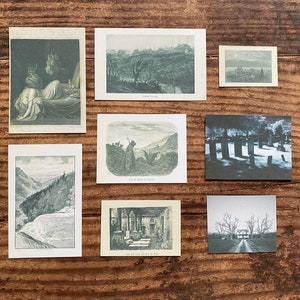 K&ouml;nnte beinhalten: Eine Sammlung von Vintage-Kunstdrucken mit Schwarz-Wei&szlig;-Illustrationen. Die Drucke zeigen verschiedene Szenen, darunter Landschaften, Figuren und architektonische Elemente. Die Drucke sind auf einer Holzoberfl&auml;che angeordnet.
