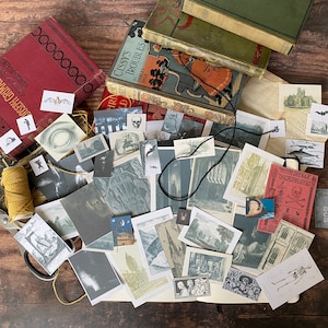 K&ouml;nnte beinhalten: Eine Sammlung von Vintage-Ephemera, darunter alte B&uuml;cher, Postkarten und Illustrationen, angeordnet auf einer Holzoberfl&auml;che. Die Artikel weisen gotische und makabre Themen auf, mit Bildern von Flederm&auml;usen, Sch&auml;deln und architektonischen Zeichnungen.