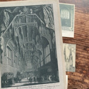 K&ouml;nnte beinhalten: Ein Schwarz-Wei&szlig;-Druck eines gro&szlig;en Saals mit gew&ouml;lbten Decken, detaillierten Fenstern und Figuren. Der Druck enth&auml;lt Text am unteren Rand mit den Worten "KING GEORGE the II". Weitere Drucke sind im Hintergrund sichtbar.