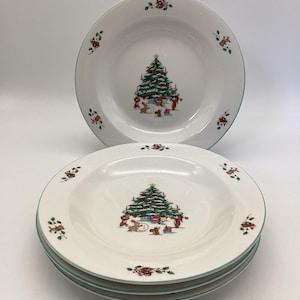 May include: White ceramic Christmas bowls with a green rim. Each bowl features a decorated Christmas tree in the center, surrounded by presents and woodland creatures. Small floral accents are placed around the rim.