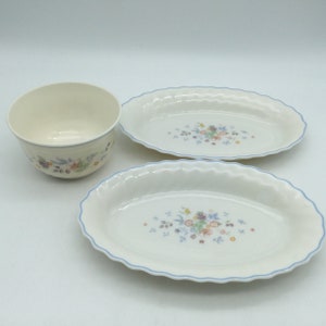 May include: A set of three white ceramic dishes with a blue and floral pattern. The set includes two oval serving dishes and a small bowl.