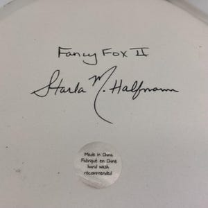 May include: Close-up of a white ceramic surface with the handwritten text "Fancy Fox II" and a signature. A small, round sticker reads "Made in China, Fabriqu&eacute; en Chine, hand wash recommended."