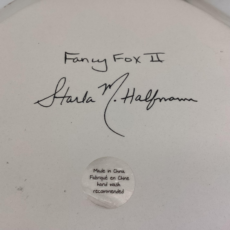 May include: Close-up of a white ceramic surface with the handwritten text "Fancy Fox II" and a signature. A small, round sticker reads "Made in China, Fabriqu&eacute; en Chine, hand wash recommended."