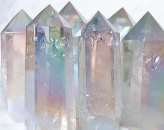 May include: A group of seven iridescent clear quartz crystal points. The points are arranged in a row, with the largest point in the center. The points are all about the same size and shape, and they have a beautiful iridescent sheen.