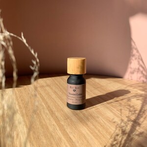 May include: A small black bottle with a wooden cap, labeled "Eco Love Wooden Cabin Essential Oils -  Evergreen, Pine, Fir & Cedar" and "10 ml".