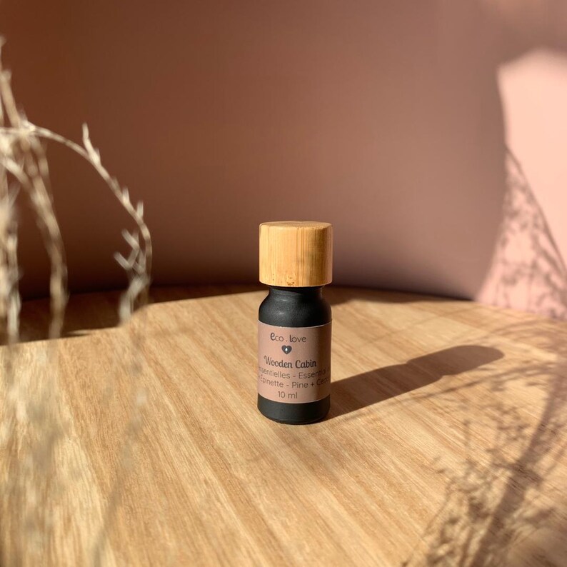 May include: A small black bottle with a wooden cap, labeled "Eco Love Wooden Cabin Essential Oils -  Evergreen, Pine, Fir & Cedar" and "10 ml".