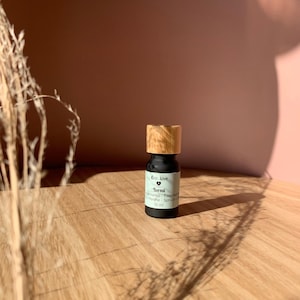 May include: A small black bottle with a wooden cap, labeled "Boreal Essential Oils - Spruce &  White Fir" and "Eco Love" with a heart symbol. The bottle contains 10 ml of essential oil.