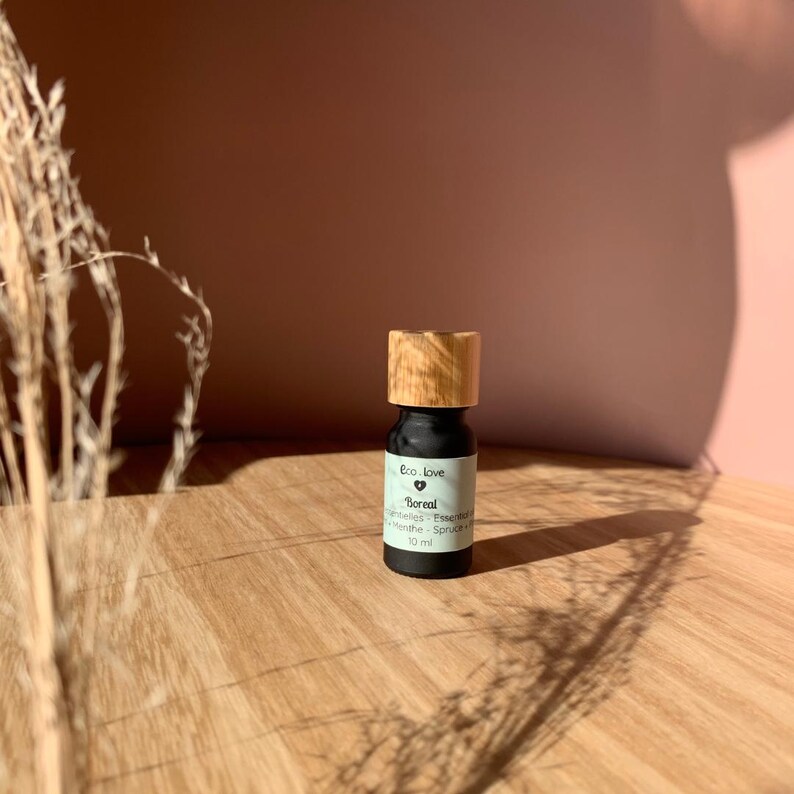 May include: A small black bottle with a wooden cap, labeled "Boreal Essential Oils - Spruce &  White Fir" and "Eco Love" with a heart symbol. The bottle contains 10 ml of essential oil.