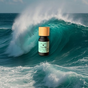 May include: A small, dark brown essential oil bottle with a light brown wooden cap. The label reads "Ocean Mist" and "10 ml". The bottle is set against a backdrop of a large, turquoise ocean wave.