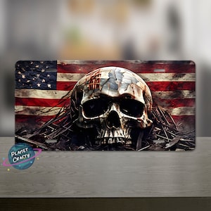 May include: A metal license plate featuring a distressed American flag with a skull in the center. The skull is cracked and has a red stripe across the forehead.