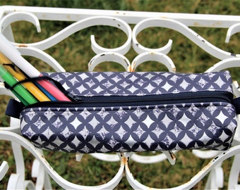 May include: A blue and white pencil case with a geometric pattern. The case has a zipper closure and a black strap. The case is filled with colorful pens.