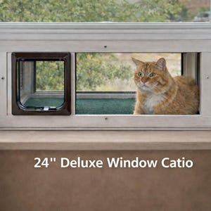 May include: A 24-inch Deluxe Window Catio, featuring a brown cat inside. The catio is built into a window frame with a cat door. The cat is orange and white with green eyes. The window looks out onto a green, leafy background.