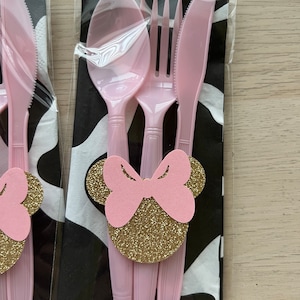 Puede incluir: Juego de cubiertos de pl&aacute;stico rosa con un dise&ntilde;o de Minnie Mouse con lazo rosa y purpurina dorada. El juego incluye un tenedor, un cuchillo y una cuchara.