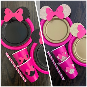 Puede incluir: Art&iacute;culos de fiesta de Minnie Mouse en rosa y negro, incluyendo platos, vasos y pajitas. Los platos tienen un centro negro y un borde rosa, con una cabeza de Minnie Mouse negra con orejas rosas y un lazo en la parte superior. Los vasos son rosas con una cabeza de Minnie Mouse negra con orejas rosas y un lazo en la parte superior. Las pajitas son blancas con lunares rosas.