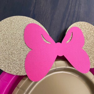 Puede incluir: Orejas de papel con purpurina dorada y un lazo rosa, perfectas para una fiesta tem&aacute;tica de Minnie Mouse.