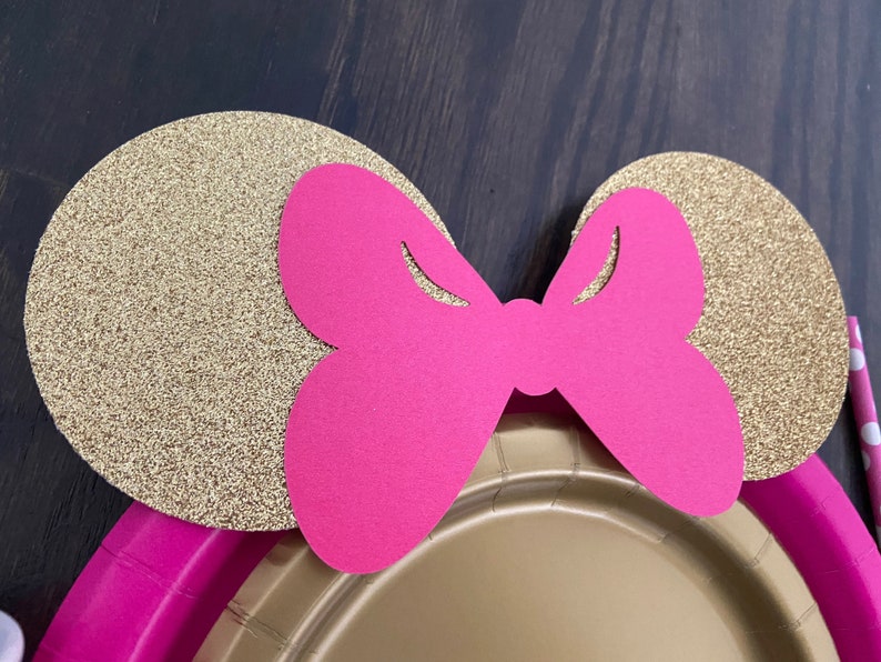 Puede incluir: Orejas de papel con purpurina dorada y un lazo rosa, perfectas para una fiesta tem&aacute;tica de Minnie Mouse.