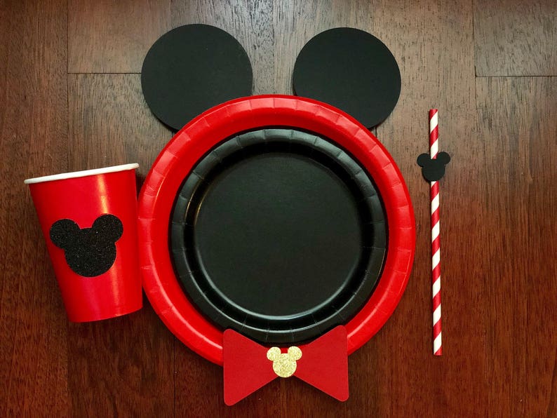 Puede incluir: Un juego de fiesta con tem&aacute;tica de Mickey Mouse, que incluye una taza y platos rojos con una silueta negra. Tambi&eacute;n incluye una pajita a rayas rojas y blancas, orejas negras y una pajarita roja con centro dorado. Ideal para una fiesta tem&aacute;tica.