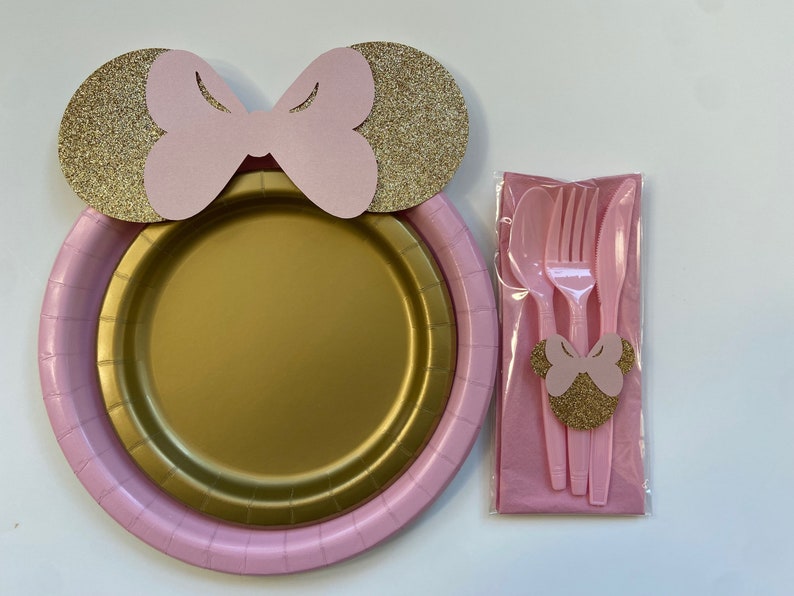 Puede incluir: Platos de fiesta rosa y dorado con un dise&ntilde;o de lazo de Minnie Mouse. Los platos se empaquetan con tenedores, cucharas y cuchillos de pl&aacute;stico rosa.