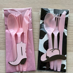 May include: Two sets of pink plastic cutlery with a pink napkin. One set has a pink cowboy boot and the other has a pink cowboy hat.
