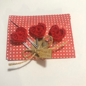 May include: Set of four red crocheted heart-shaped paper clips with a brown tag that says "Hugs & Stitches" tied with twine.