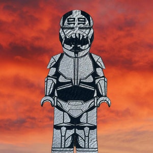 May include: A silver and black Lego minifigure of a Stormtrooper with a black helmet and a black chest piece.