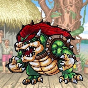 May include: A green and brown embroidered patch of a cartoon character with red hair and a shell on its back. The character has a large mouth and sharp teeth. The patch is on a wooden background.