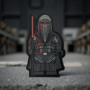 May include: A black and gray patch featuring a stylized figure in a helmet and armor, holding a red lightsaber. The design includes red accents on the helmet and armor, with a dark background.