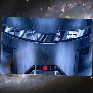 May include: A close-up of a robot's face. The robot has a metallic blue and gray exterior with a red and black stripe across the bottom. The robot's eyes are glowing red.