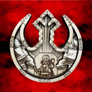 May include: A wooden laser-cut ornament featuring the Rebel Alliance symbol with a Star Wars character inside. The symbol is white and the character is black.